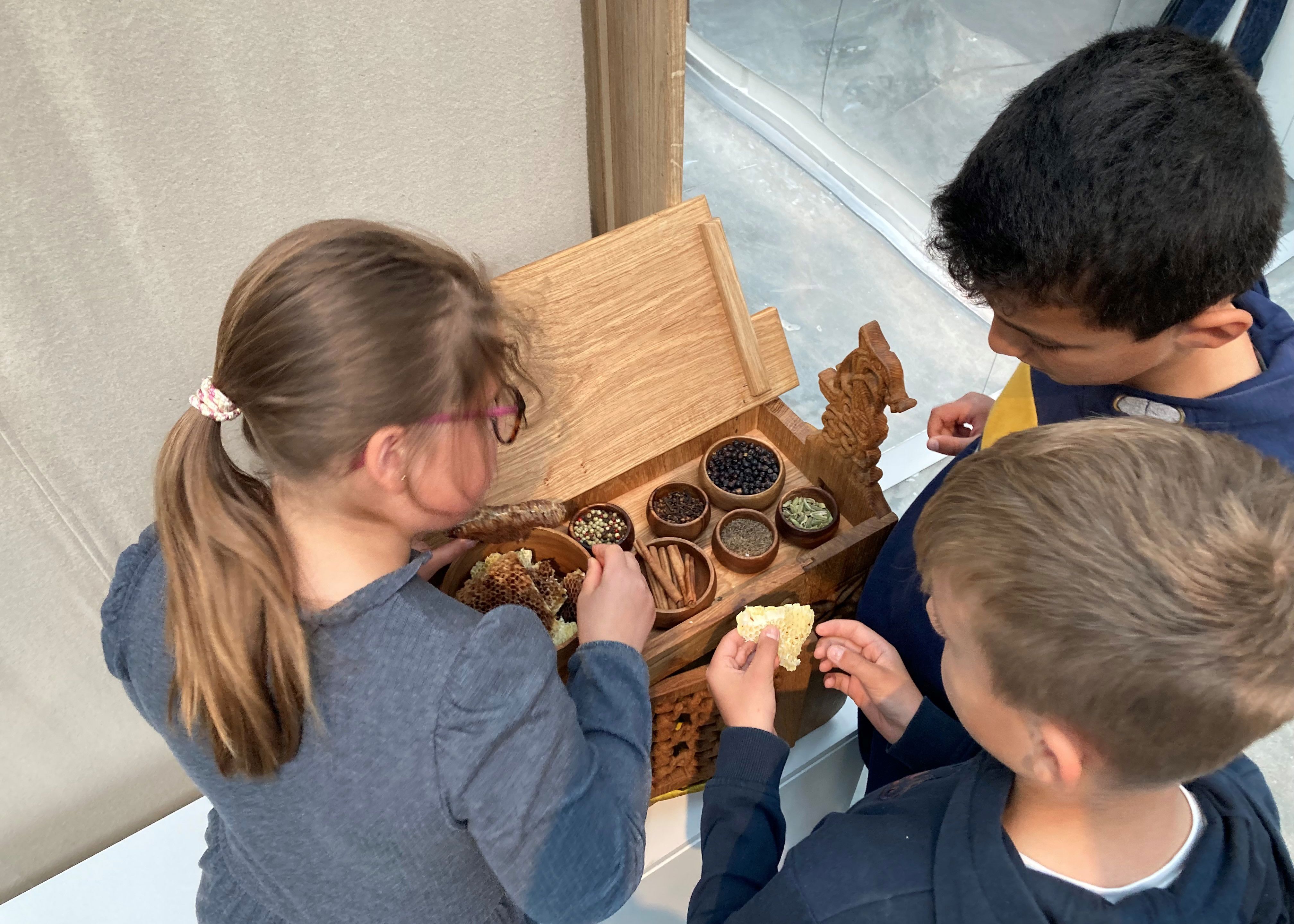 Tre børn dufter og mærker i udstillingen Magt og guld